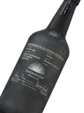 Primer plano de la botella de vidrio oscuro de Mezcal Casamigos Joven artesanal.