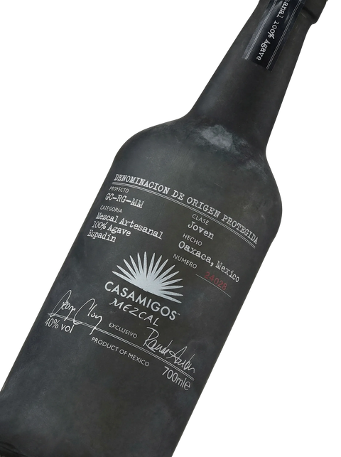 Primer plano de la botella de vidrio oscuro de Mezcal Casamigos Joven artesanal.
